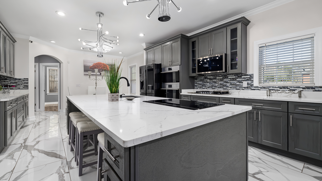 Modern gray kitchen with a marble island, stainless steel appliances, and a glass tile backsplash.